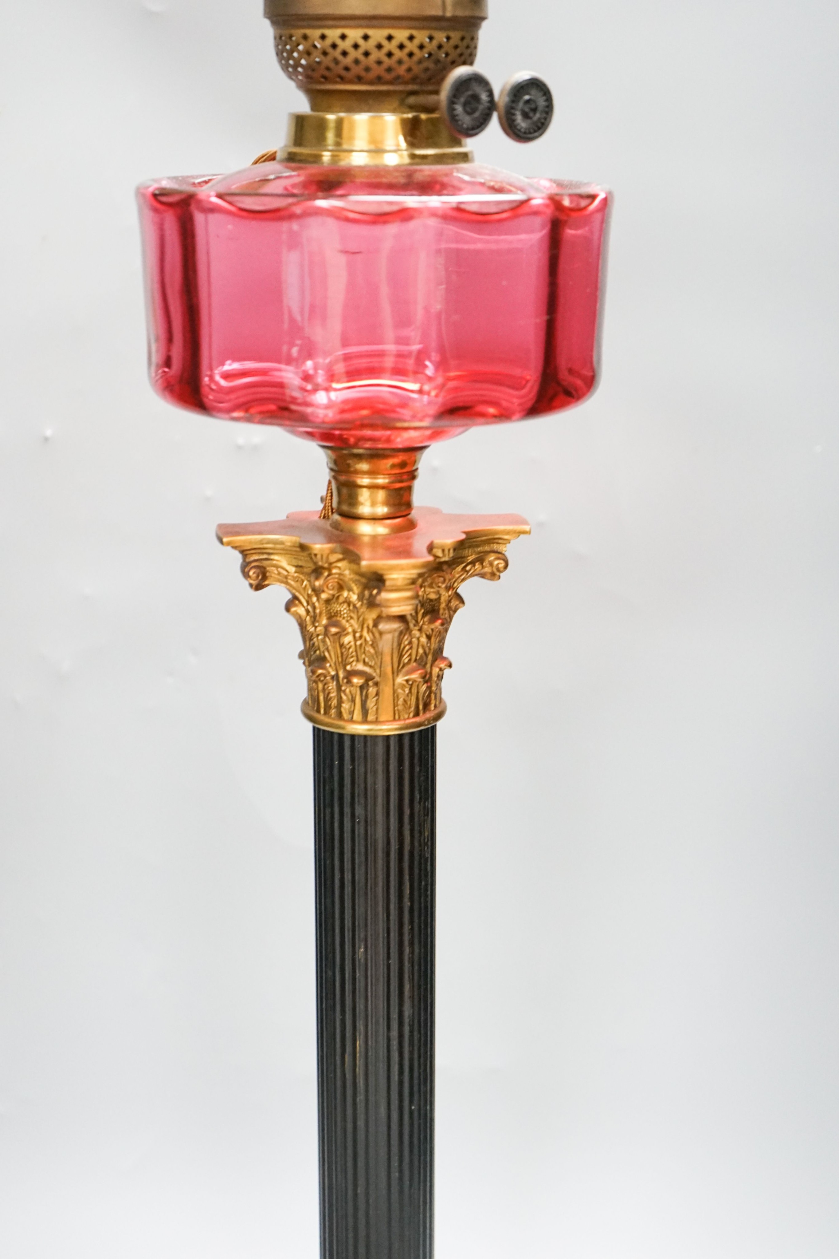 And early 20th century Corinthian column brass and cranberry glass oil lamp, converted for electricity, total height 70 cm